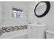 Well-lit bathroom featuring mosaic tiling in the bathtub and a classic round mirror at 4249 Dubarry Rd, Indianapolis, IN 46226