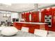 Open concept kitchen with red cabinets, an island cooktop, modern appliances, and a view into the living space at 501 Fletcher Ave # D, Indianapolis, IN 46203