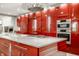 Modern kitchen features red cabinetry, stainless steel appliances, and a center island with a cooktop at 501 Fletcher Ave # D, Indianapolis, IN 46203