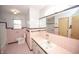 Well-lit bathroom features pink tile, a framed mirror and a sink with cabinet storage underneath at 5502 Radnor Rd, Indianapolis, IN 46226