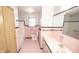 Bathroom featuring pink floor tiles, tile walls, standard toilet, and a large mirror at 5502 Radnor Rd, Indianapolis, IN 46226