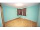Bedroom featuring light hardwood floors, teal walls, window with blinds, and a flush ceiling light at 5502 Radnor Rd, Indianapolis, IN 46226