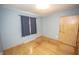 Bedroom features gray walls, light hardwood floors, and window with dark curtains, and a light wood closet door at 5502 Radnor Rd, Indianapolis, IN 46226