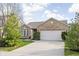 Well-maintained brick home with a two-car garage, manicured bushes, and a lush green lawn at 6537 Amherst Way, Zionsville, IN 46077