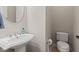 Chic half-bath features a pedestal sink, oval mirror, and modern toilet, creating a stylish and functional space at 6691 Beekman Pl, Zionsville, IN 46077