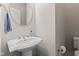 Chic half-bath features a pedestal sink, oval mirror, and modern toilet, creating a stylish and functional space at 6691 Beekman Pl, Zionsville, IN 46077