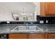 Close-up of a stainless steel kitchen sink with a modern faucet, set against dark countertops and tiled backsplash at 6691 Beekman Pl, Zionsville, IN 46077