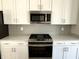 Close-up of a kitchen featuring stainless steel appliances, white cabinets, and a grey tiled backsplash at 6882 Equality Blvd, Carmel, IN 46033