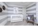 Charming Bedroom featuring a white crib, gray rocking chair, and playful giraffe-themed decor against striped walls at 7156 Firestone Rd, Whitestown, IN 46052