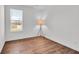 Minimalist bedroom with hardwood floors, a large window, and a standing lamp at 7450 Leatherwood Dr, Indianapolis, IN 46259