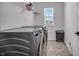 Efficient laundry room with modern machines, bright window, and storage shelves at 7450 Leatherwood Dr, Indianapolis, IN 46259