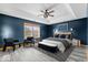 Spacious main bedroom featuring a tray ceiling, a ceiling fan, an expansive window, and light wood flooring at 8333 Hunters Meadow Ct, Indianapolis, IN 46259