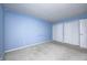 An empty room features light blue walls, neutral carpet, and double closets for ample storage at 11363 Kristen Ln, Indianapolis, IN 46235