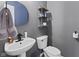 Gray powder room features a pedestal sink, toilet, shelving, and a decorative mirror at 11614 Presidio Dr, Indianapolis, IN 46235