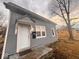 Low angle view of the house exterior featuring a white front door and three windows at 1425 W 9Th St, Anderson, IN 46016