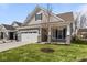 Attractive home with a two-car garage, lush green lawn, and stone-accented pillars on the covered porch at 16771 Cattle Hollow Ln, Noblesville, IN 46060
