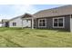Exterior shot of the house features large windows, covered patio, and a sprawling green lawn at 16771 Cattle Hollow Ln, Noblesville, IN 46060