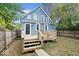 Backyard view of a blue home with a wood deck, mature trees, and a partially fenced-in yard at 2528 Guilford Ave, Indianapolis, IN 46205