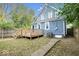 Backyard view of a blue home with a wood deck, mature trees, and a partially fenced-in yard at 2528 Guilford Ave, Indianapolis, IN 46205