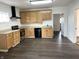 Well-lit kitchen with light wood cabinets, dark laminate floors, and modern black appliances at 2712 S A St, Elwood, IN 46036