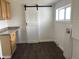 Bright laundry room features modern sliding barn door, dark wood flooring, window, and utility connections at 2712 S A St, Elwood, IN 46036