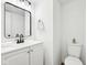Bathroom featuring a sleek mirror, sink, toilet, and white cabinets at 3155 N White River Pkwy E Dr, Indianapolis, IN 46208