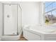 Bright bathroom featuring a walk-in shower and a soaking tub with a window view at 3155 N White River Pkwy E Dr, Indianapolis, IN 46208