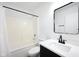Clean bathroom featuring a sleek black framed mirror, white sink, and shower with a black rod at 3155 N White River Pkwy E Dr, Indianapolis, IN 46208