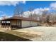 View of detached garage with multiple bays, side porch and gravel driveway on a partly cloudy day at 316 Elm St, Greenwood, IN 46142