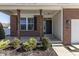 Inviting covered front porch with brick columns, manicured shrubs, and a black front door at 4063 S Meadow Wood Ct, New Palestine, IN 46163