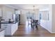 Open-concept kitchen and dining area with stainless steel appliances, white cabinetry, and modern lighting at 4063 S Meadow Wood Ct, New Palestine, IN 46163
