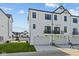 Rear view showcasing modern townhome with attached garages and small balconies overlooking a green lawn at 4180 Douro Trl, Westfield, IN 46062