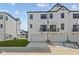 Back facade of a contemporary townhome with garages and a balcony overlooking a manicured lawn at 4180 Douro Trl, Westfield, IN 46062