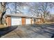 Attached two-car garage with a brick exterior and an asphalt driveway on a sunny day at 4808 N Tuxedo St, Indianapolis, IN 46205