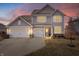 Elegant two-story home with a three-car garage and inviting warm lights highlighting the facade at dusk at 5646 Mahogany Dr, Noblesville, IN 46062