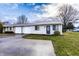 Charming one-story home features a front lawn, driveway, garage, and classic architecture under a cloudy sky at 8004 Minlo Dr, Indianapolis, IN 46227