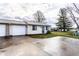 Charming one-story home features a front lawn, driveway, garage, and classic architecture under a cloudy sky at 8004 Minlo Dr, Indianapolis, IN 46227