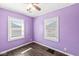 Bright purple bedroom with two windows and wood-look floors is a vibrant space at 103 S Delawanda Ave, Muncie, IN 47303