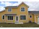 Rear view of a bright yellow two-story home with modern windows and a well-manicured lawn at 10483 St Anne Dr, Zionsville, IN 46077