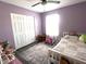 Bright bedroom with purple walls, ceiling fan, wood floors and a neutral area rug at 1217 Meadowood Dr, Danville, IN 46122