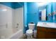 Bright blue bathroom showcasing a shower-tub combo, toilet, and sink with vanity and mirror at 1288 Ivory Ct, Greenwood, IN 46143