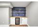 Close-up of bar area with stylish blue tile backsplash, wooden shelves, white cabinets, and beverage fridge at 1422 Carrollton Ave, Indianapolis, IN 46202