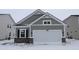 Charming home exterior featuring a gray facade, brick accents, and a two-car garage, complemented by a snow-covered yard at 1841 James Pierce Dr, Shelbyville, IN 46176