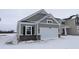 Charming gray home with a white garage door, black shutters, and brick accents nestled on a snow-covered lawn at 1841 James Pierce Dr, Shelbyville, IN 46176