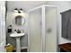 Bathroom featuring pedestal sink, frosted glass shower, and round mirror at 19 Orchard Ln, Anderson, IN 46011