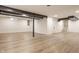 Spacious basement featuring light wood flooring, a support beam, and stairs leading up to another level at 220 Pine Dr, Indianapolis, IN 46260