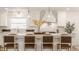 Beautiful kitchen island with bar stool seating, white cabinets, modern light fixtures and stylish decor at 220 Pine Dr, Indianapolis, IN 46260