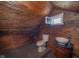 Unique bathroom featuring wood-paneled walls, toilet, vessel sink with antique-style vanity, and a window at 300 E North Main St, Summitville, IN 46070