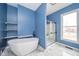 Bathroom featuring free standing tub, glass shower and blue walls at 300 E North Main St, Summitville, IN 46070