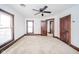 A spacious bedroom with fresh white paint, neutral carpet, ceiling fan, and wood-trimmed doors and windows at 300 E North Main St, Summitville, IN 46070